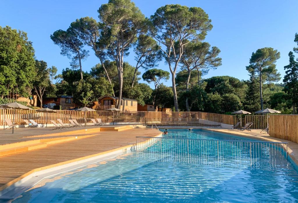 une grande piscine avec une terrasse en bois dans l'établissement Huttopia Forêt de Janas, à La Seyne-sur-Mer
