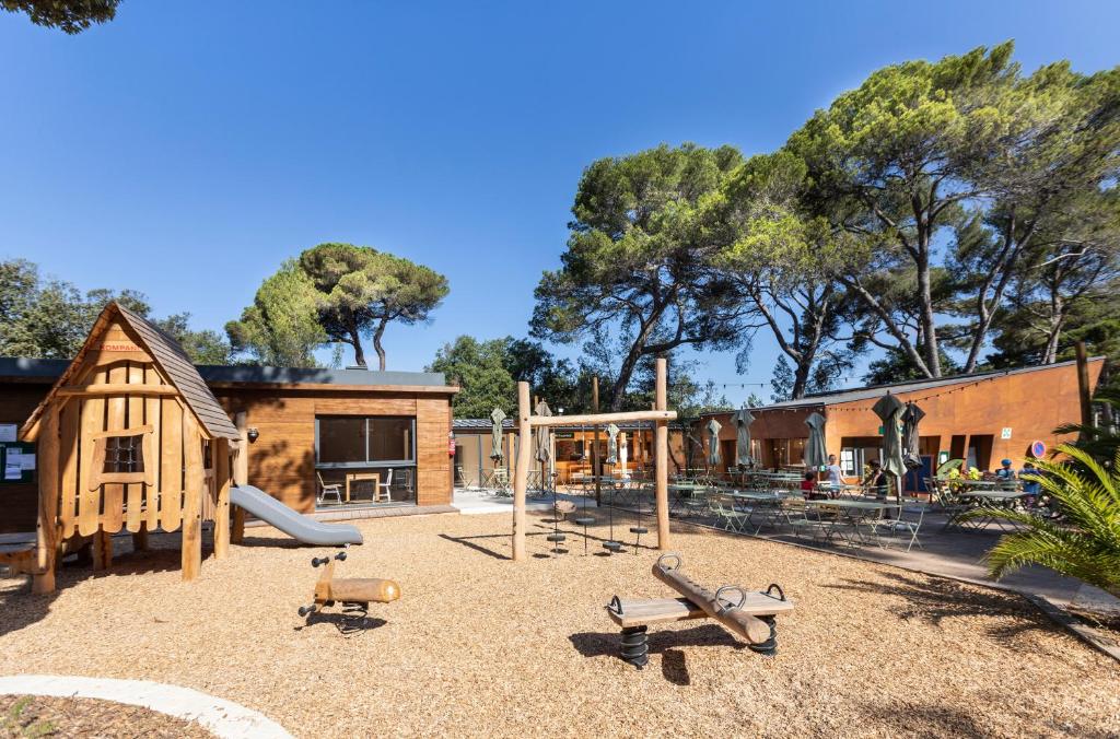 une aire de jeux avec balançoire et un bâtiment dans l'établissement Huttopia Forêt de Janas, à La Seyne-sur-Mer