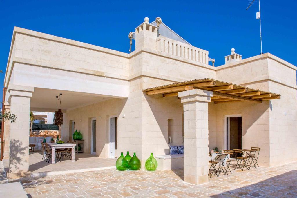 - un bâtiment avec une terrasse dotée d'une table et de chaises dans l'établissement Antica Pietra - Villa con piscina in Puglia, à Ostuni