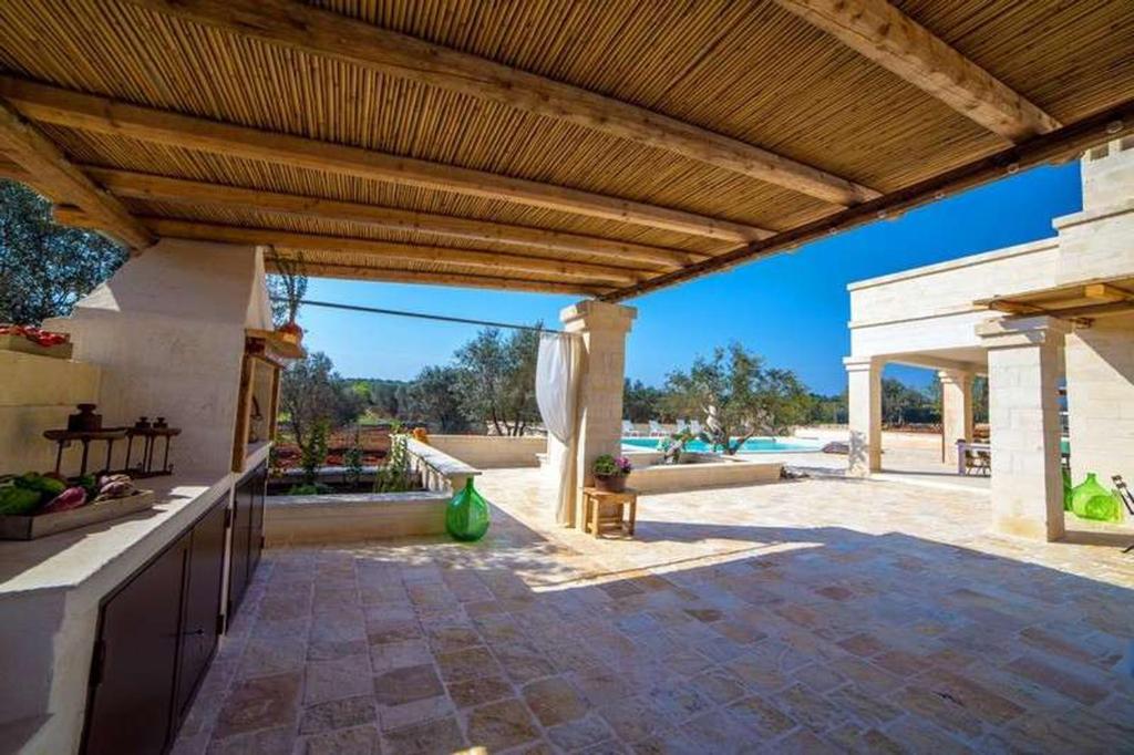 une cuisine extérieure avec un toit en bois et une terrasse dans l'établissement Antica Pietra - Villa con piscina in Puglia, à Ostuni