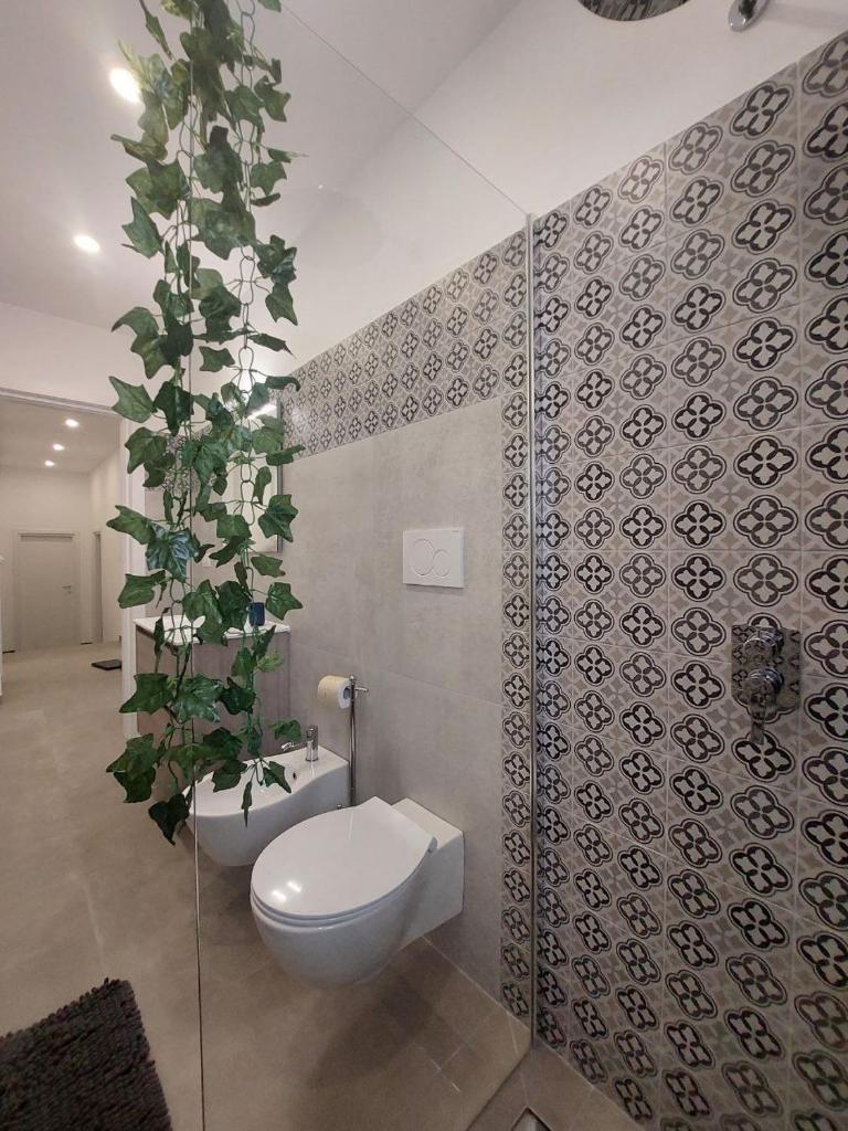 La salle de bains est pourvue de toilettes et d'une plante murale. dans l'établissement Tropical Palm Villa, à Monopoli