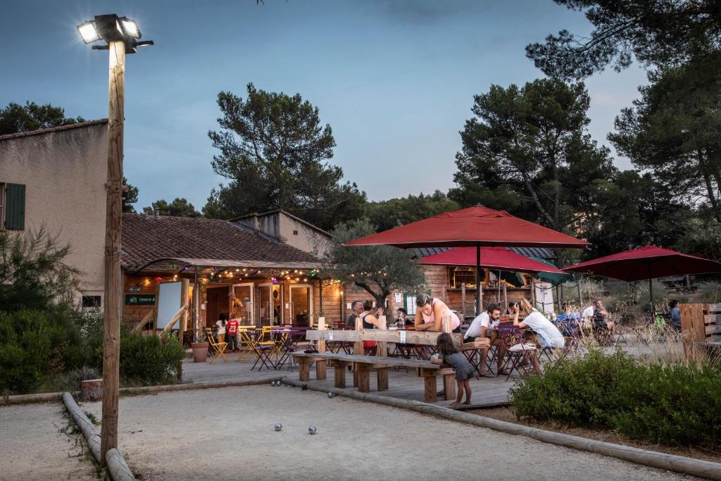 un groupe de personnes assises à une table avec des parasols dans l'établissement Huttopia Fontvieille, à Fontvieille
