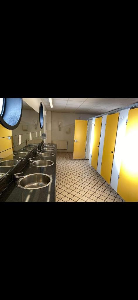 La salle de bains est pourvue d'une rangée de lavabos et de cales jaunes. dans l'établissement Miraflores, à Boulogne-sur-Mer