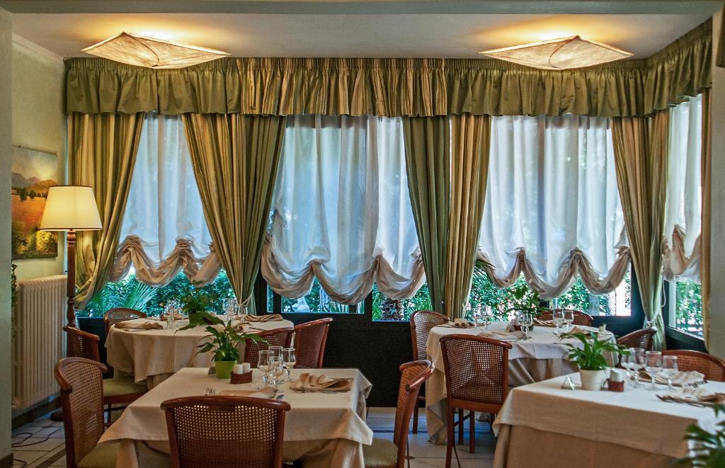 un restaurant avec des tables, des chaises et des rideaux dans l'établissement Hotel Kyrton, à Forte dei Marmi