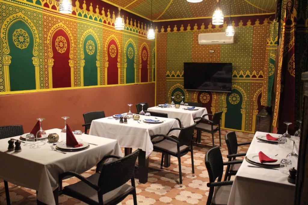 une salle à manger avec tables et chaises et une télévision dans l'établissement Riad Hilmuna Hammam et Spa, à Marrakech