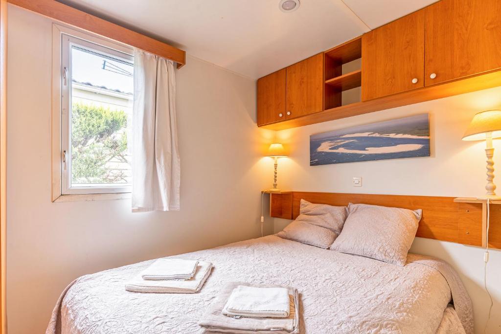 une petite chambre avec un lit et une fenêtre dans l'établissement Mobilhome bord de mer Gujan Mestras, à Gujan-Mestras