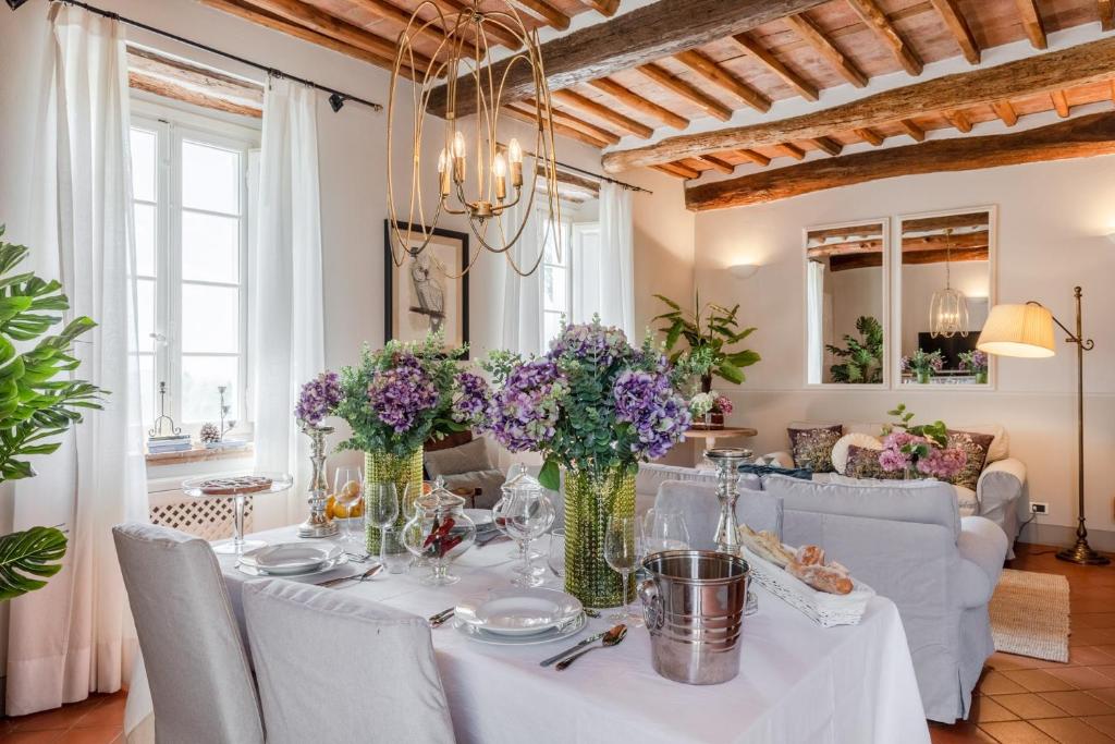une salle à manger avec une table avec des fleurs violettes dans des vases dans l'établissement Fattoria Camigliano, Luxury Farmhouse with Pool inside a Wine Estate, à Capannori 61 autres photos