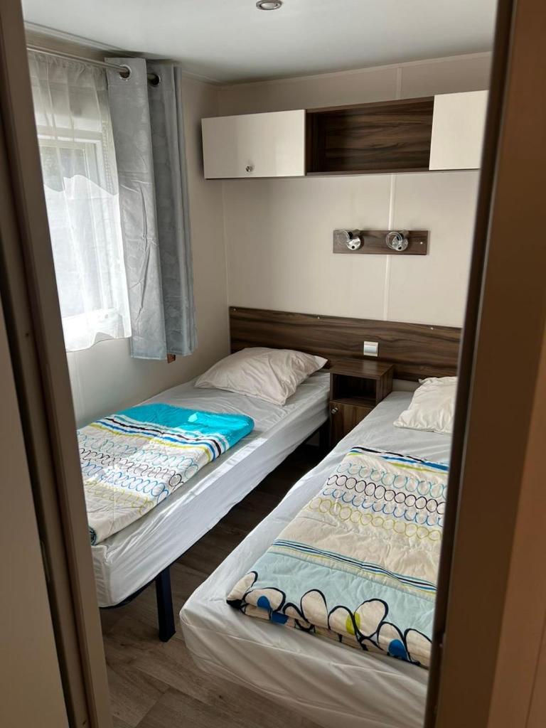 deux lits jumeaux dans une chambre avec fenêtre dans l'établissement Camping les Cigales - Mobil-home 4/6 personnes, au Muy