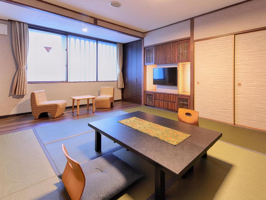 une pièce avec une table, des chaises et une télévision dans l'établissement Gion Shinmonso, à Kyoto