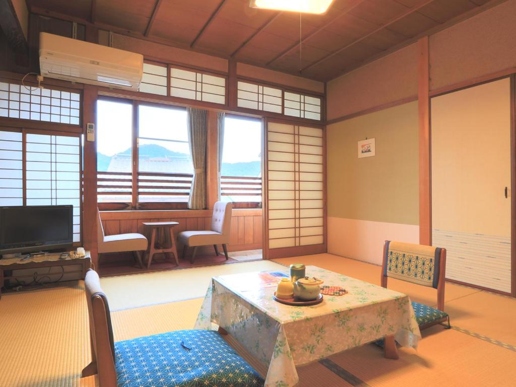 un salon avec une table, des chaises et une télévision dans l'établissement Ougiya Ryokan, à Toyooka