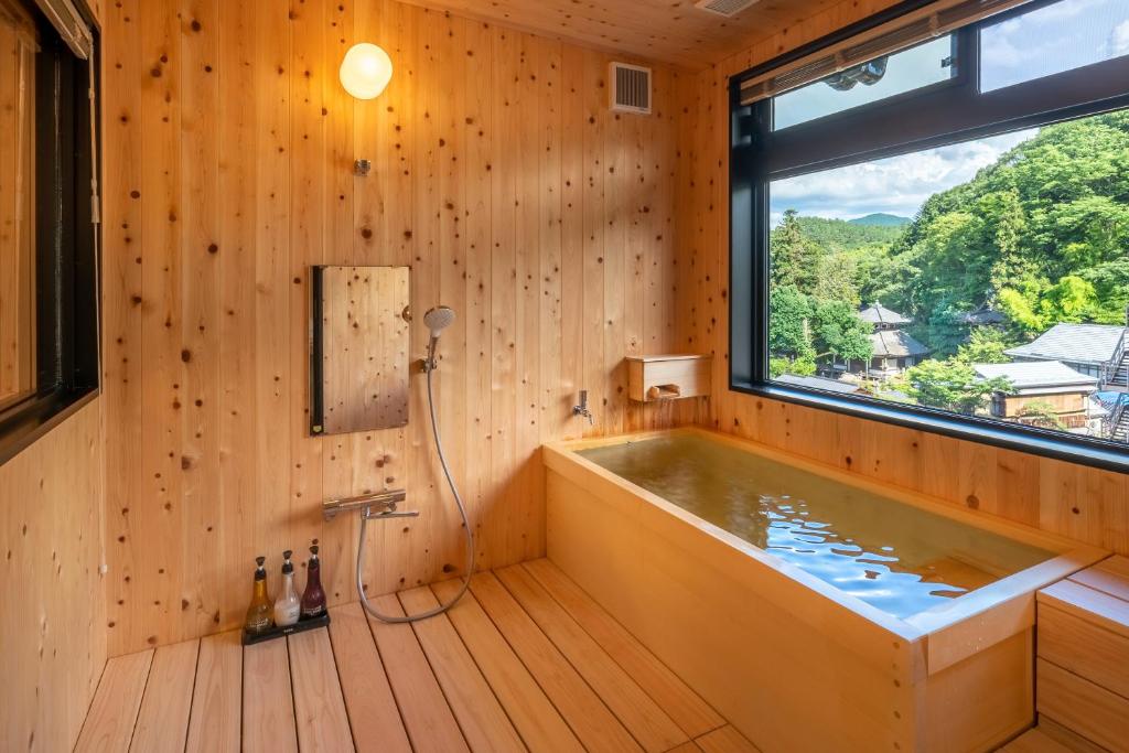 La salle de bains en bois est pourvue d'une baignoire et d'une fenêtre. dans l'établissement Nakamatsuya Ryokan, à Ueda