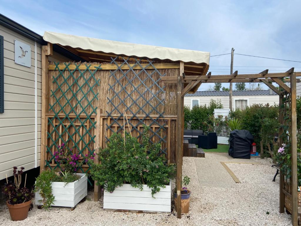un jardin avec une pergola en bois et des plantes en pot dans l'établissement Vos meilleures vacances au Montourey!, à Fréjus