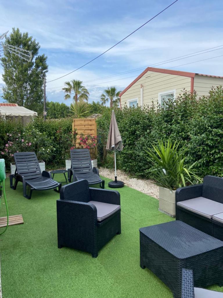 une terrasse avec des chaises et des tables sur de l'herbe verte dans l'établissement Vos meilleures vacances au Montourey!, à Fréjus