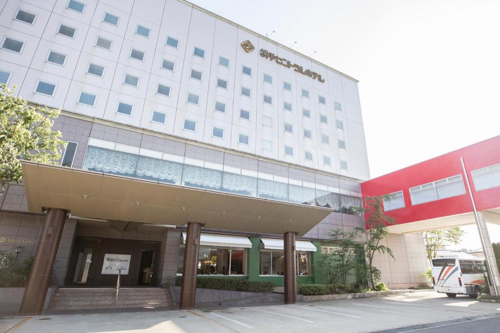 un grand bâtiment avec un bus garé devant lui dans l'établissement Yokote Central Hotel, à Yokote