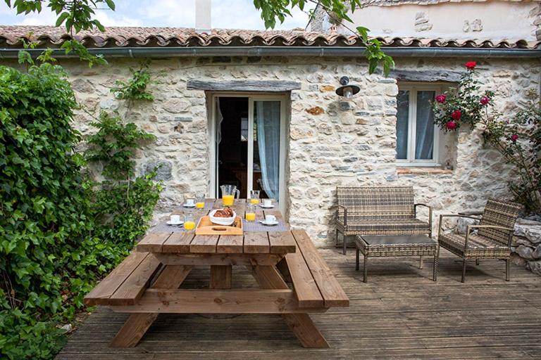 - une table de pique-nique en bois devant une maison en pierre dans l'établissement Gîtes du Lamalou, à Notre-Dame-de-Londres