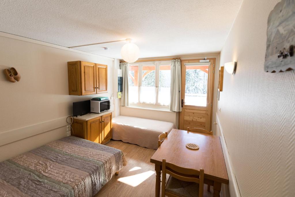 - une petite chambre avec un lit, un bureau et une table dans l'établissement Studio Lou Kiwi - Résidence Bec de l Aigle, à Le Lioran