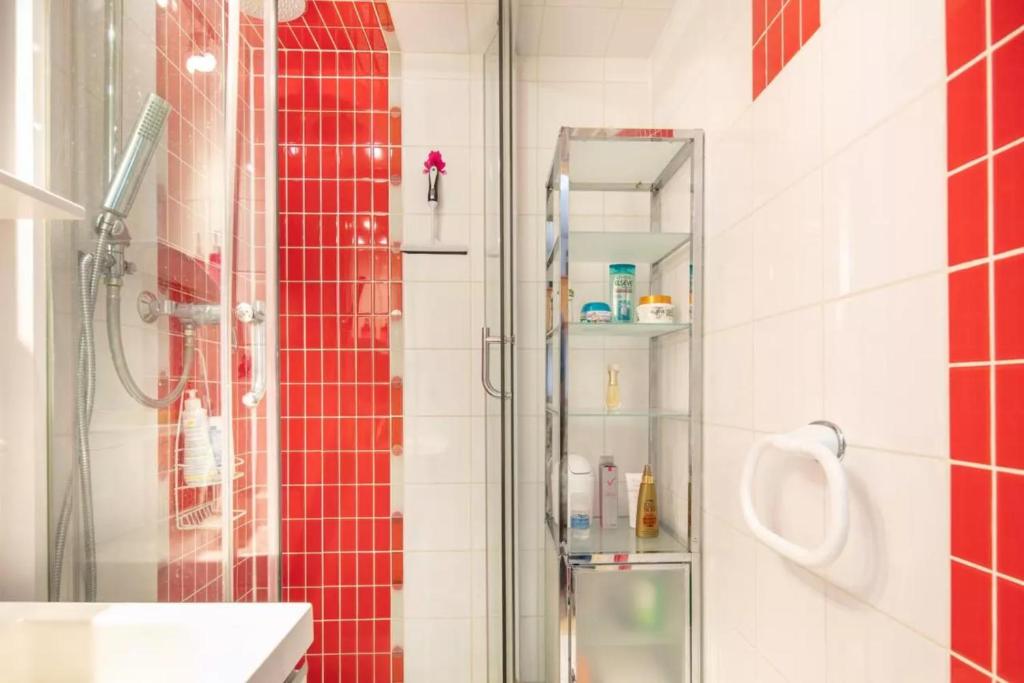 La salle de bains est pourvue d'une douche et de carrelage rouge. dans l'établissement Séjour Grand Ski, à Huez