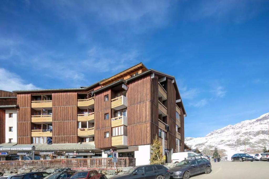 un bâtiment avec des voitures garées devant lui dans l'établissement Séjour Grand Ski, à Huez