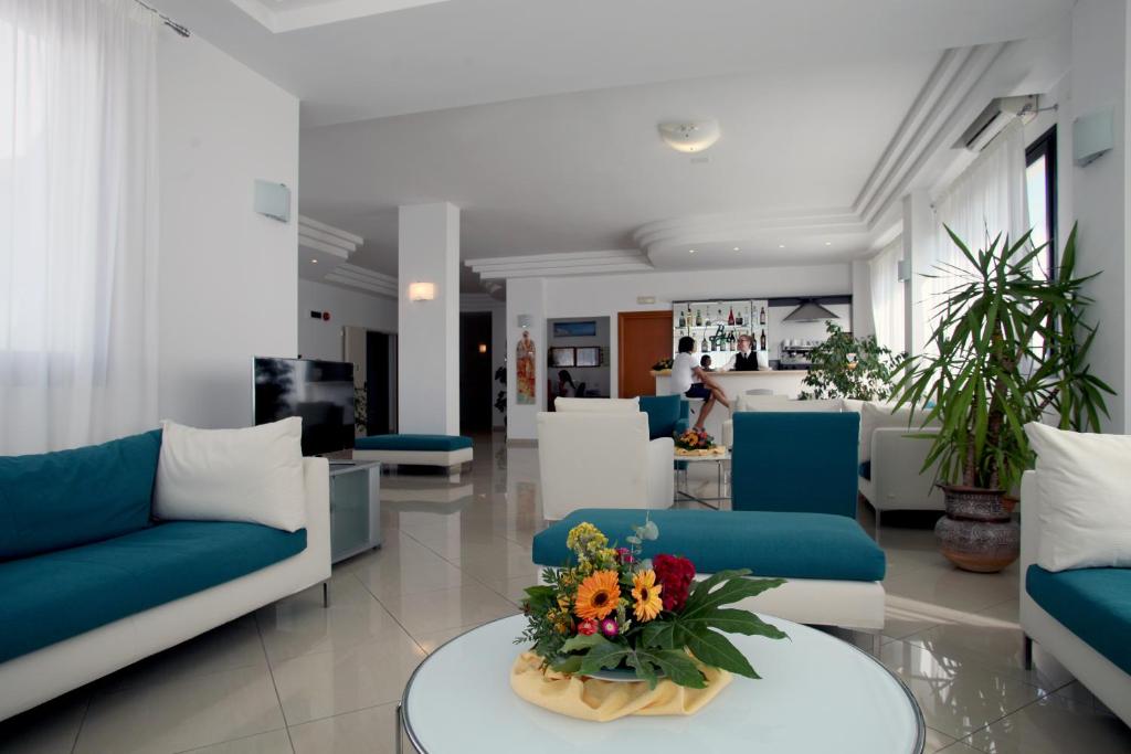 un salon avec des canapés bleus et des fleurs sur une table dans l'établissement Bikini Hotel, à Vieste