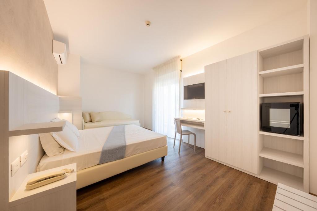 une chambre blanche avec un lit et un bureau dans l'établissement Hotel Corfù, à Pineto
