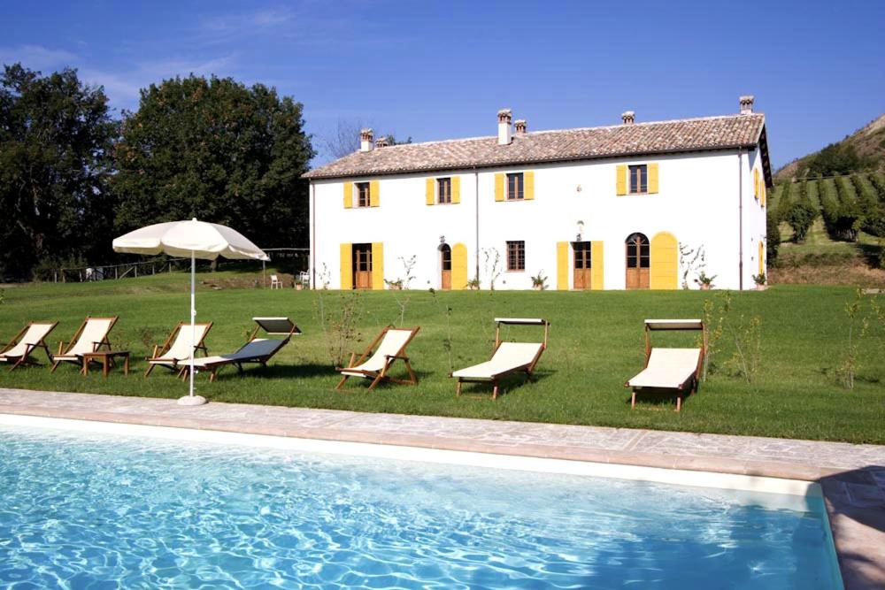 - un groupe de chaises et un parasol à côté d'une maison dans l'établissement Villa Il Cigno, à Brisighella