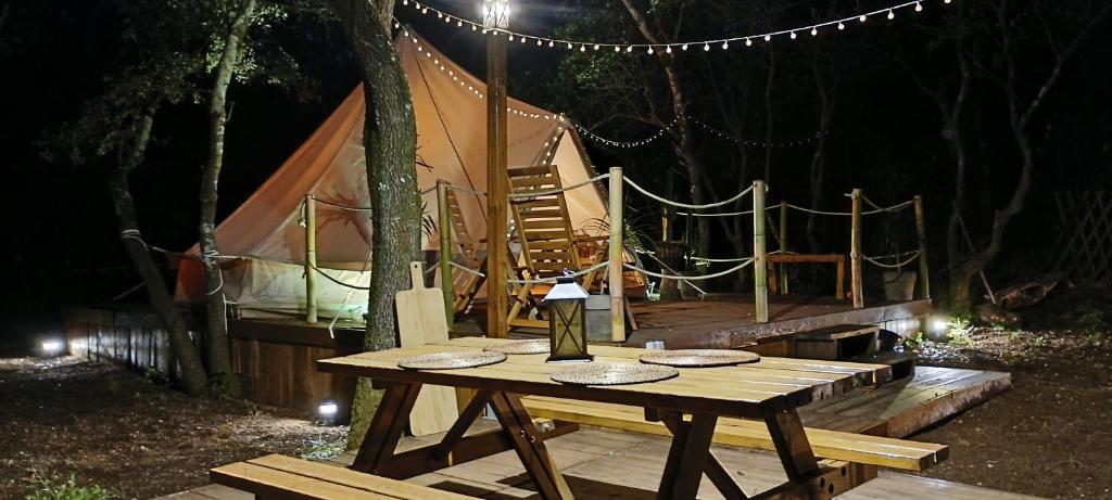 une table de pique-nique avec une lampe et une tente la nuit dans l'établissement Évasion en pleine nature, Tipi insolite et Jacuzzi au Pont du Gard !, à Vers-Pont-du-Gard