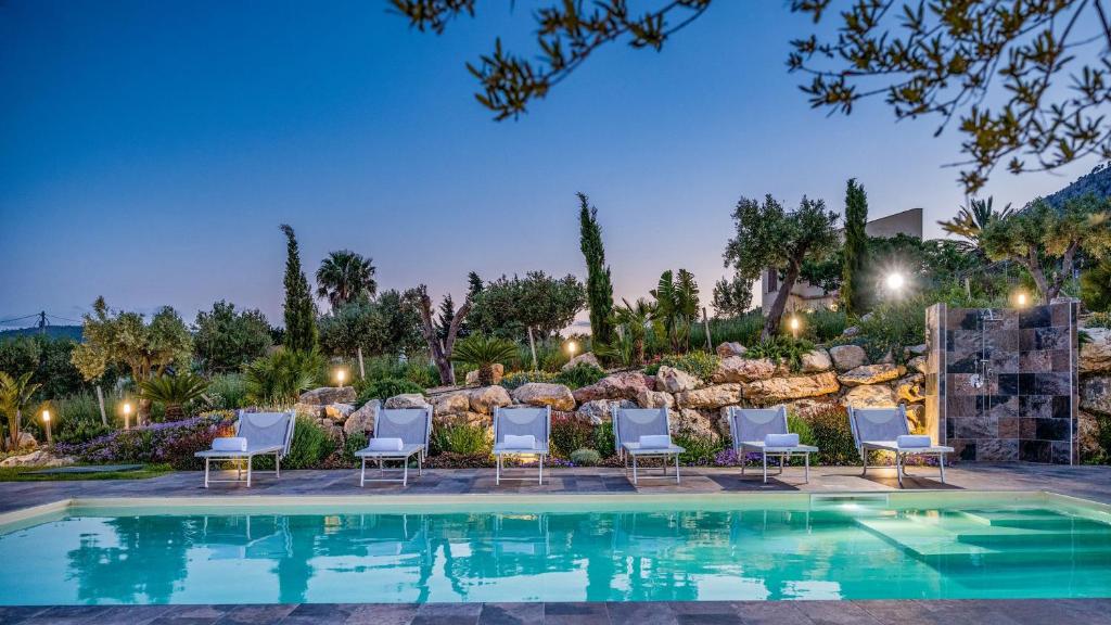 - une piscine avec des chaises et un mur en pierre dans l'établissement DAMA DEI VENTI 6&2, Emma Villas, à Castellammare del Golfo