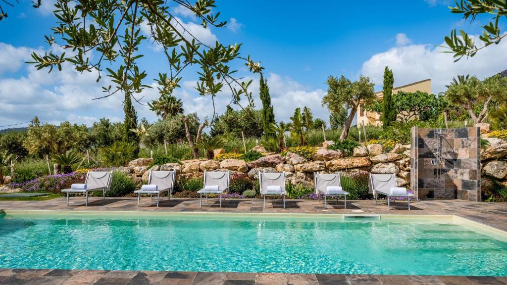 une piscine dans un complexe hôtelier avec des chaises et un mur d'escalade dans l'établissement DAMA DEI VENTI 6&2, Emma Villas, à Castellammare del Golfo