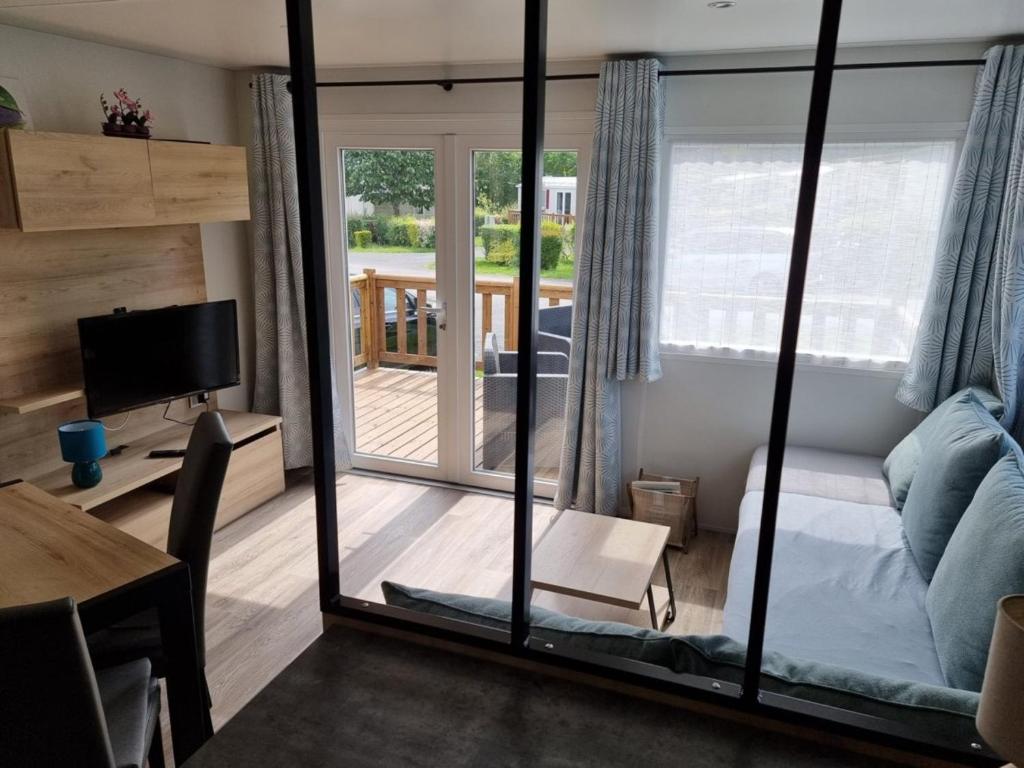 Cette chambre comprend un lit et une porte coulissante en verre. dans l'établissement Mobil-home 2023 RapidHome Panorama 3 chambres 6 vélos lave-vaisselle 2 piscines couvertes, à Litteau