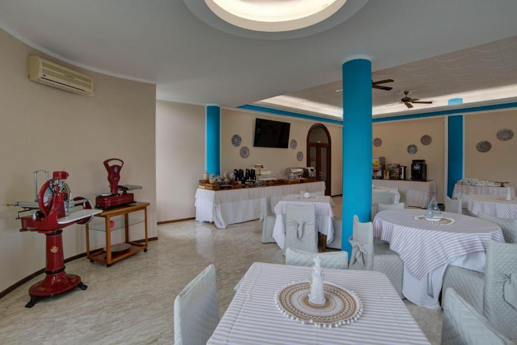 une salle à manger avec des tables blanches et des piliers bleus dans l'établissement Hotel Sporting, à Vasto