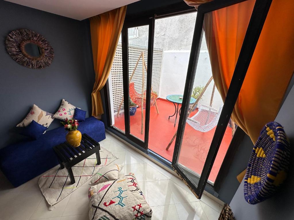 un salon avec un canapé bleu et une grande fenêtre dans l'établissement Riad 7 Pierres, à Essaouira
