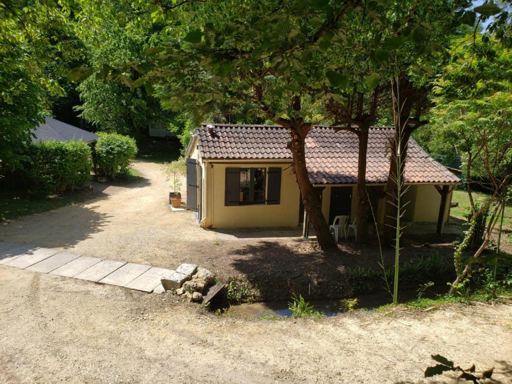 une petite maison jaune au milieu d'une cour dans l'établissement Camping EAU NATURELLE 2 étoiles Bungalow ou Tente 4 personnes dans un environnement calme et dépaysant, à Tursac