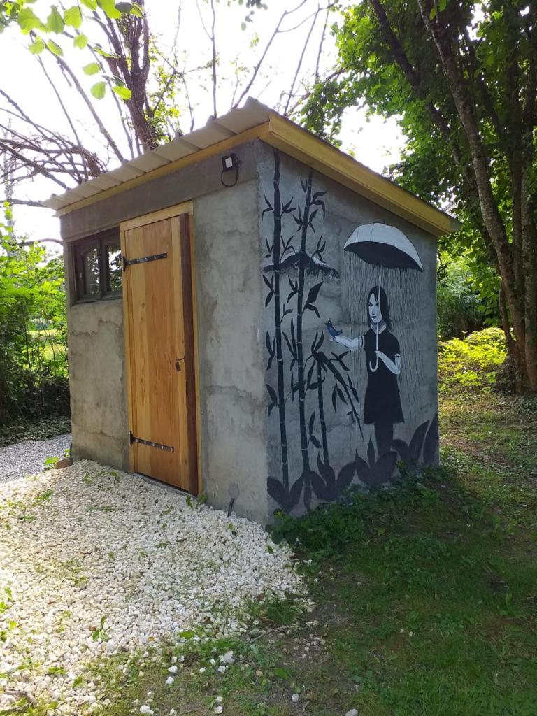un bâtiment avec une peinture représentant une femme tenant un parapluie dans l'établissement Bulle sous les étoiles, à La Saunière 1 autre photo