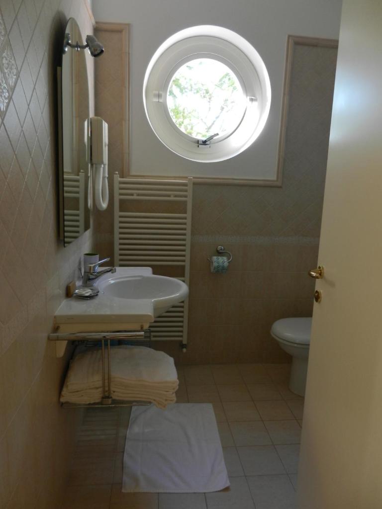 une salle de bain avec un lavabo et une fenêtre ronde dans l'établissement Residence Xenia, à Alba Adriatica