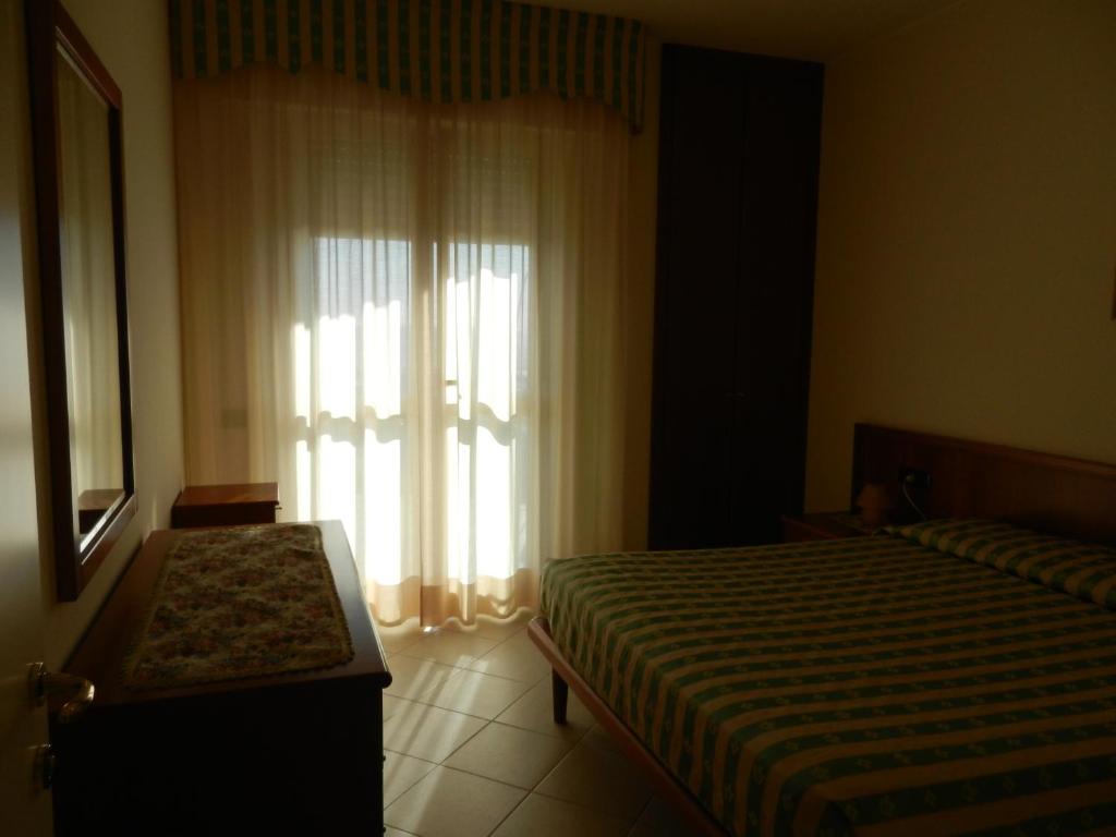 une chambre avec un lit et une fenêtre avec des rideaux dans l'établissement Residence Xenia, à Alba Adriatica