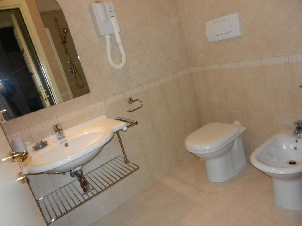 une salle de bain avec un lavabo et des toilettes et un téléphone dans l'établissement Residence Xenia, à Alba Adriatica