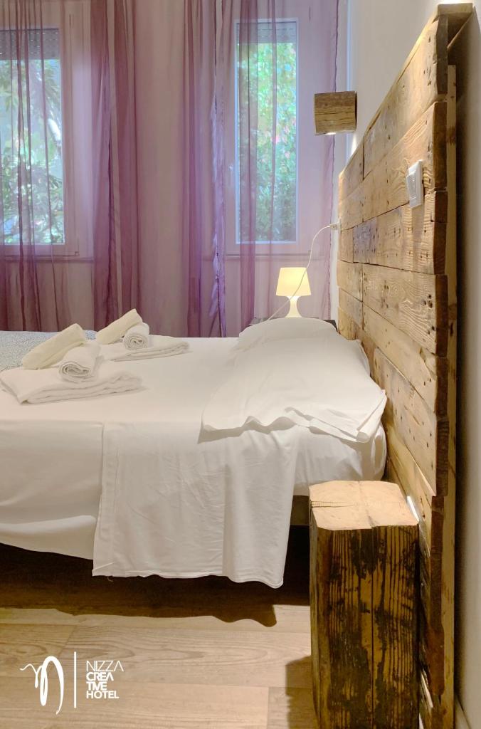 - une chambre avec un grand lit et une tête de lit en bois dans l'établissement Hotel Nizza Creative Hotel, à Rimini
