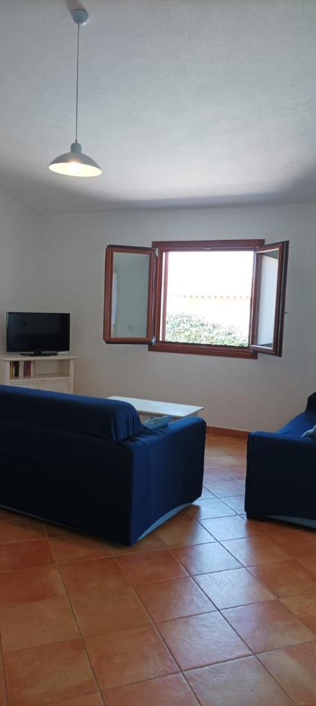 un salon avec un canapé bleu et une fenêtre dans l'établissement Villa Gallura Dream with private pool and sea view, à Tanaunella