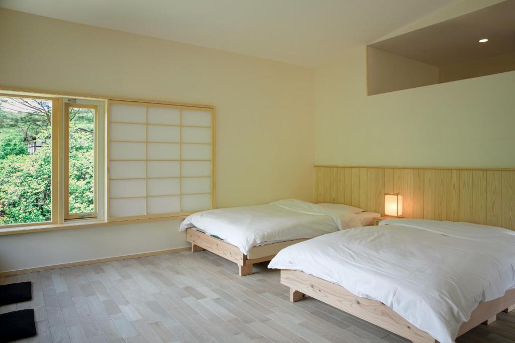 deux lits dans une chambre avec une fenêtre dans l'établissement Shiroyamakan, à Shirakawa-gō