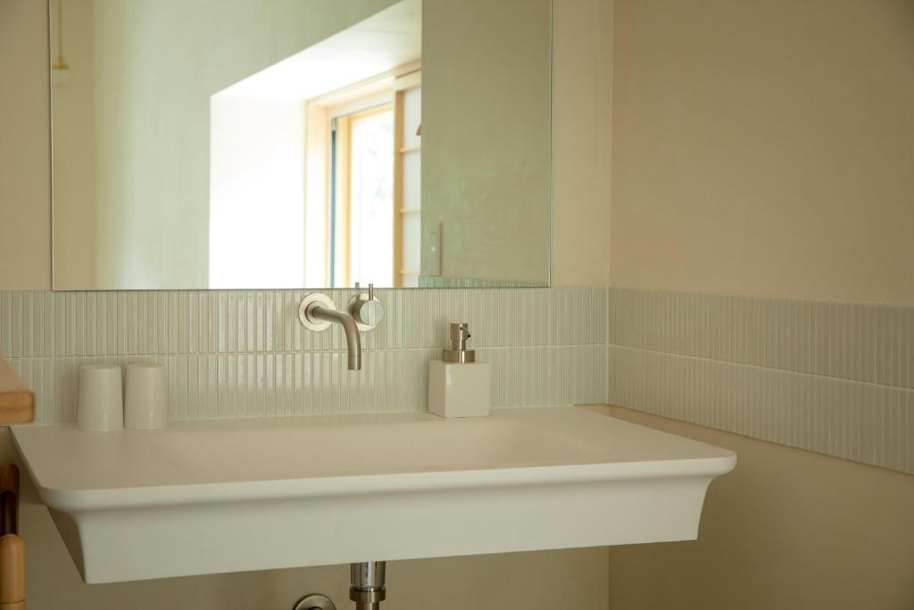 un lavabo blanc dans une salle de bain avec un miroir dans l'établissement Shiroyamakan, à Shirakawa-gō