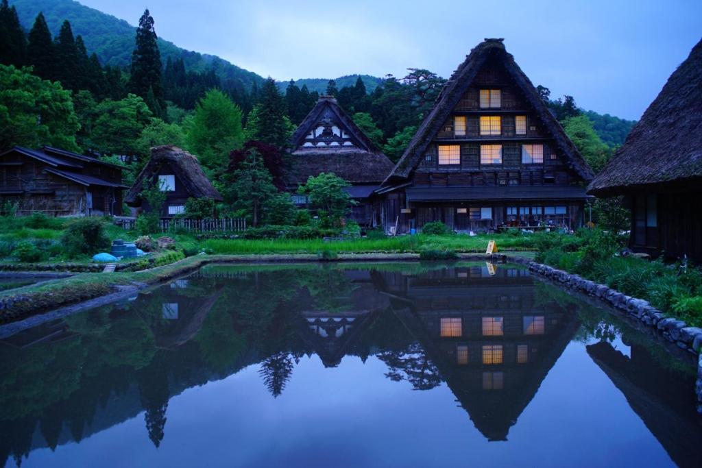 une maison avec un étang en face de celle-ci dans l'établissement Shiroyamakan, à Shirakawa-gō
