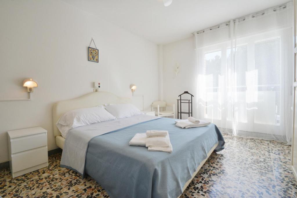 une chambre blanche avec un lit avec des serviettes dessus dans l'établissement Hotel Maddalena, à Marina di Ravenna