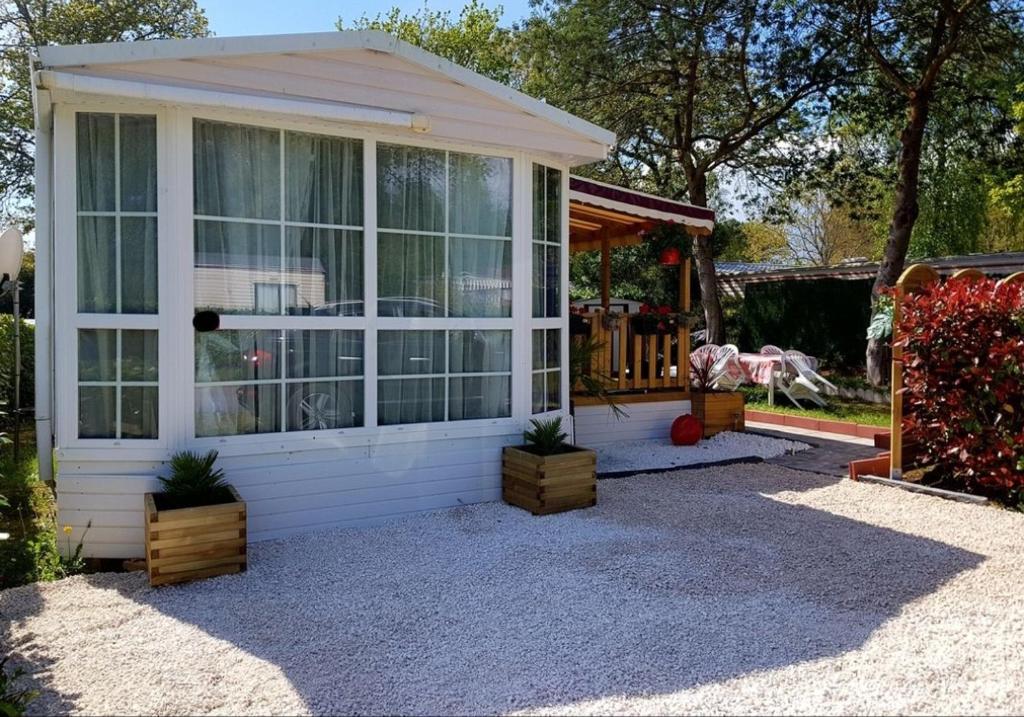 une maison blanche avec des fenêtres et des plantes dans une cour dans l'établissement LE PETIT BONHEUR, à Pont-Aven