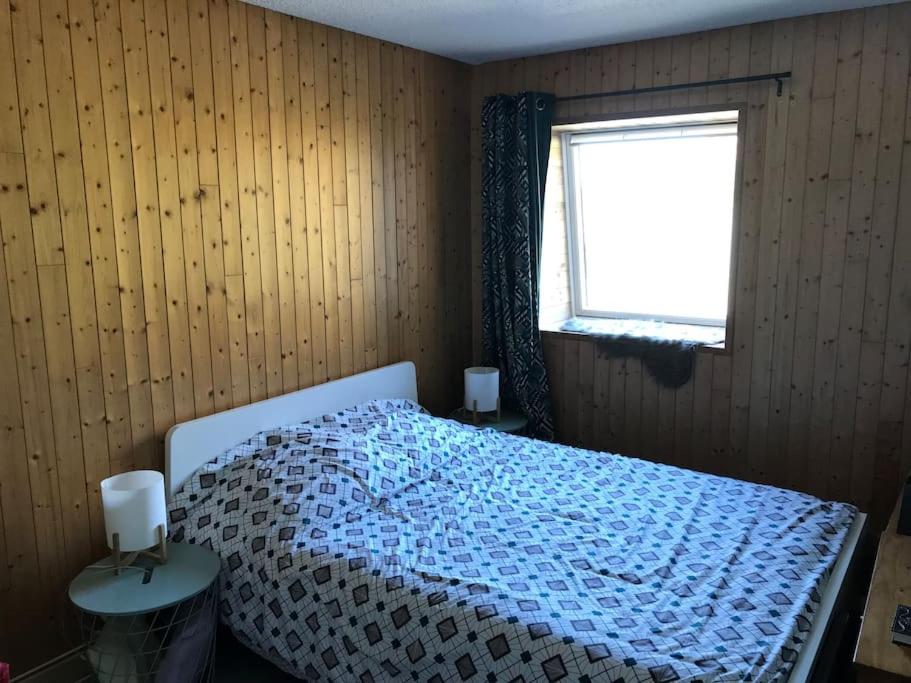 une chambre avec un lit avec une couette bleue et une fenêtre dans l'établissement Appartement spacieux au cœur du massif du Sancy, à Le Mont-Dore