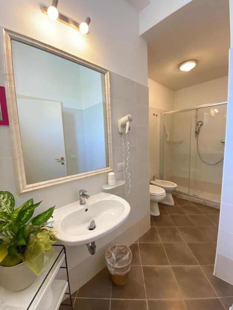 une salle de bain avec un lavabo, des toilettes et un miroir dans l'établissement Hotel Villa del Parco, à Rimini