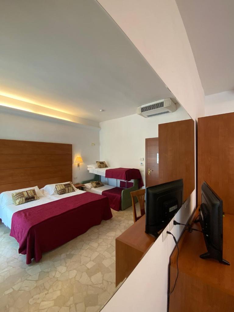 une chambre d'hôtel avec deux lits et une télévision à écran plat dans l'établissement Hotel Villa del Parco, à Rimini