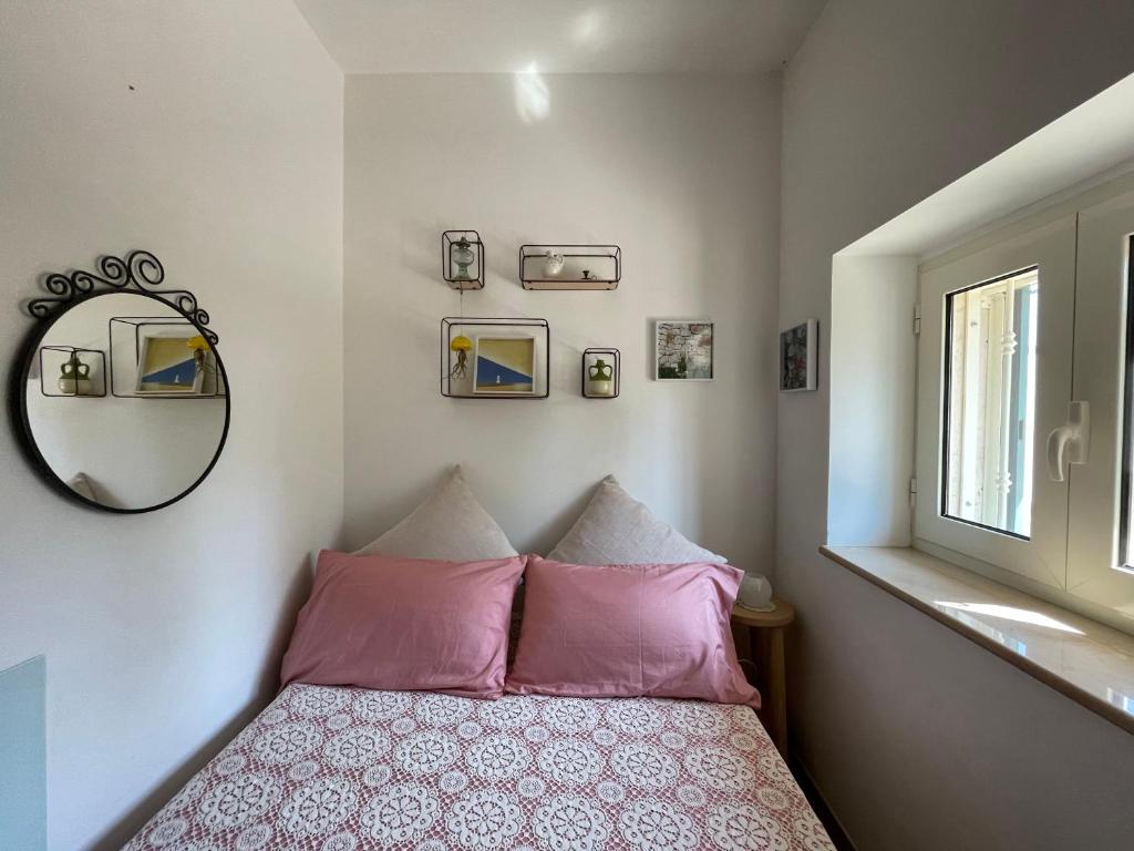 - une chambre avec un lit doté d'oreillers roses et d'un miroir dans l'établissement Trullo Trullallero, à Martina Franca