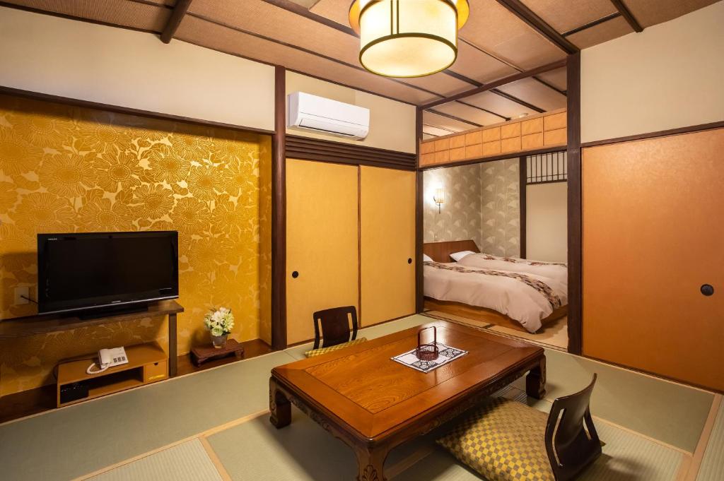 une chambre avec un lit, une table et une télévision dans l'établissement Izu atagawa Yubana mankai -Adult Only-, à Higashiizu