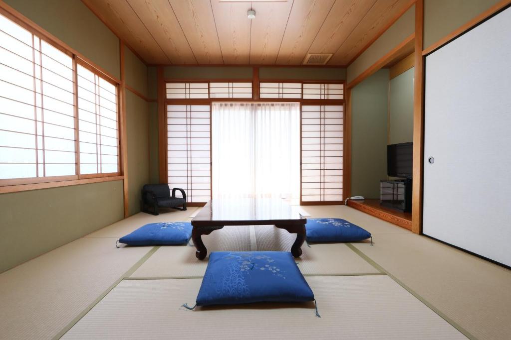 une salle de méditation avec une table et des coussins bleus dans l'établissement Naitouya, à Minamichita