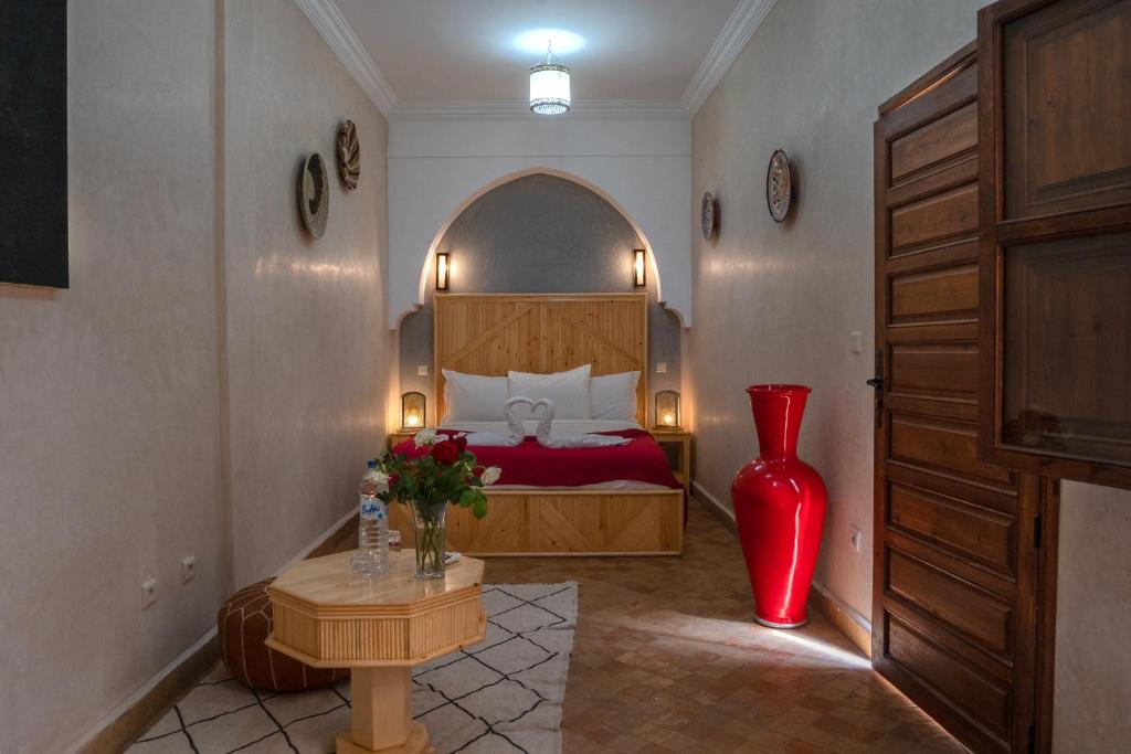 - une chambre avec un lit et un vase rouge dans l'établissement Riad Le Plein Sud, à Marrakech